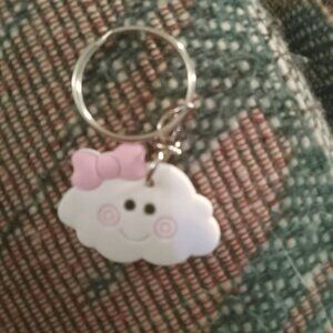 A cute cloud with a smiley face keychain.